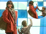 Game on: Milla Jovovich and daughter Ever occupy themselves at baggage reclaim with fun panel game