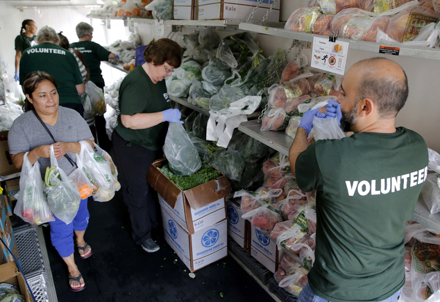 Doctors are set to give patients prescriptions to get fruit and vegetables from nearby food trucks. Pictured: Volunteers hand produce to a woman in  Oak Forest Health Center in  Illinois