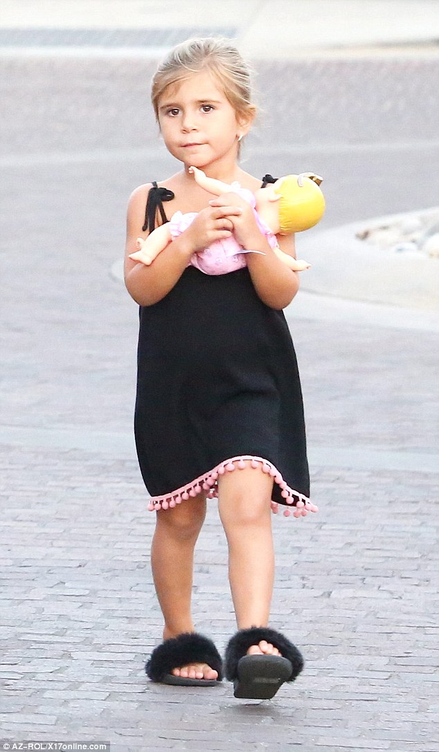 On-trend tot: Penelope - who clung hold of her dolly - was dressed in a velvet slip dress with pink bubbles and a pair of fluffy AKID slides