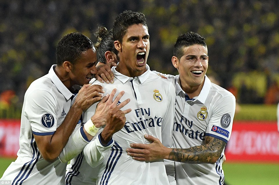 Varane is mobbed by team-mates after his late effort secures an impressive away win for the Spanish giantsÂ 